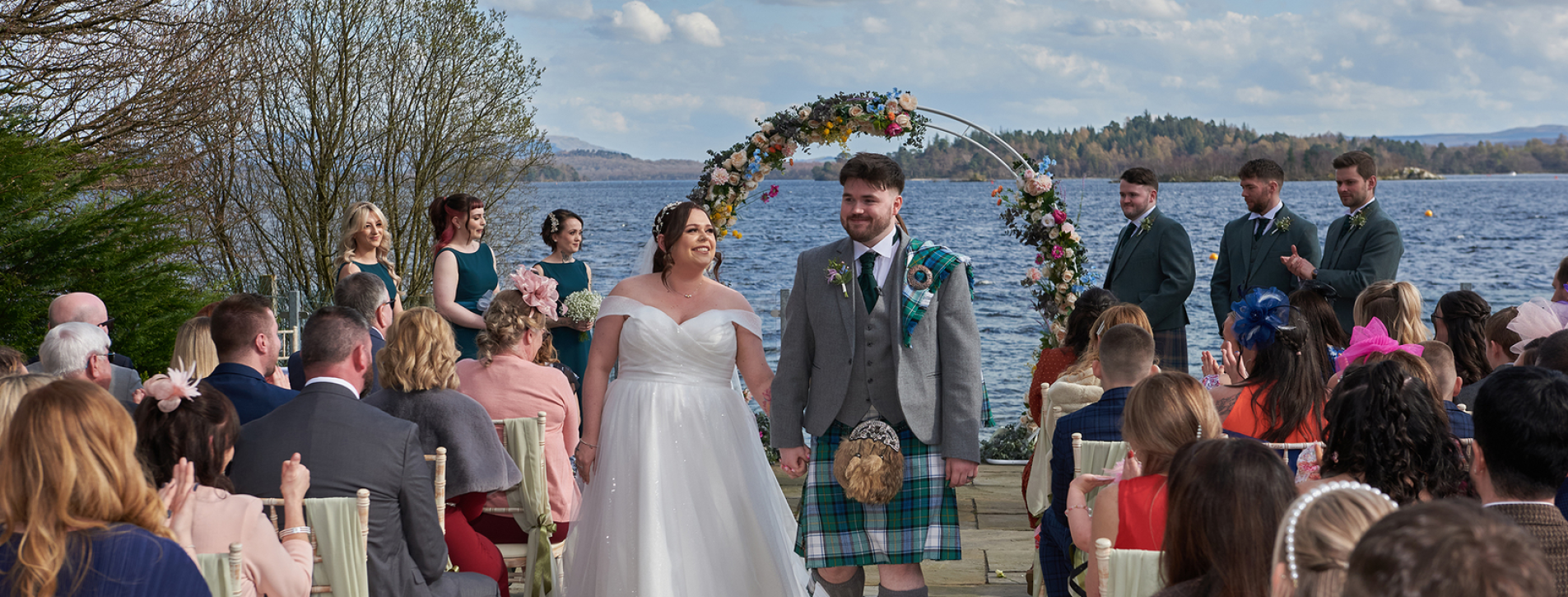 Bride and groom standing by the shore of Loch Lomond
